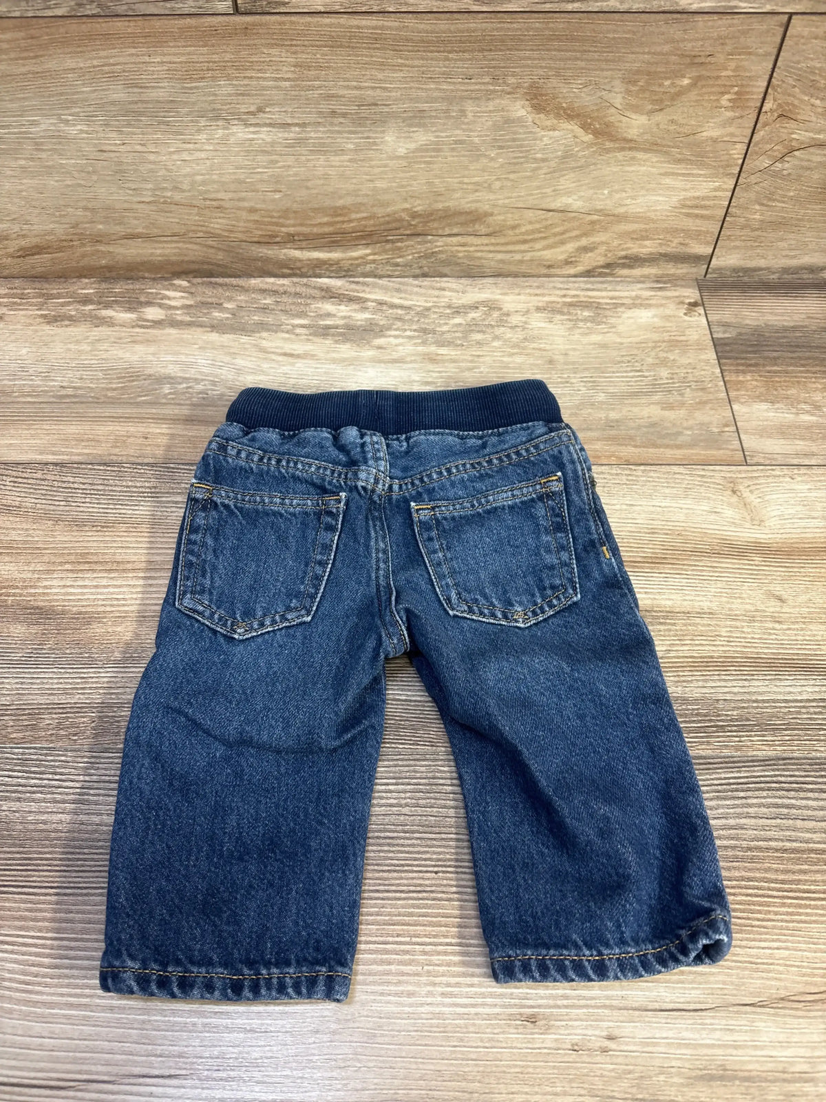 Back view of Baby Gap pull on straight baby jeans blue showing elastic waistband and back pockets on wood floor