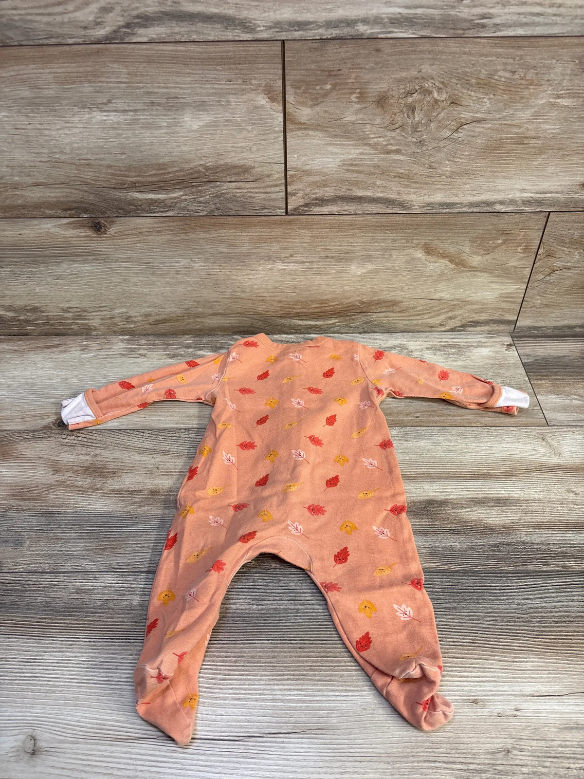 Front view of Old Navy leaf sleeper in orange, size 3 to 6 months, showcasing leaf pattern and footed legs on wood flooring