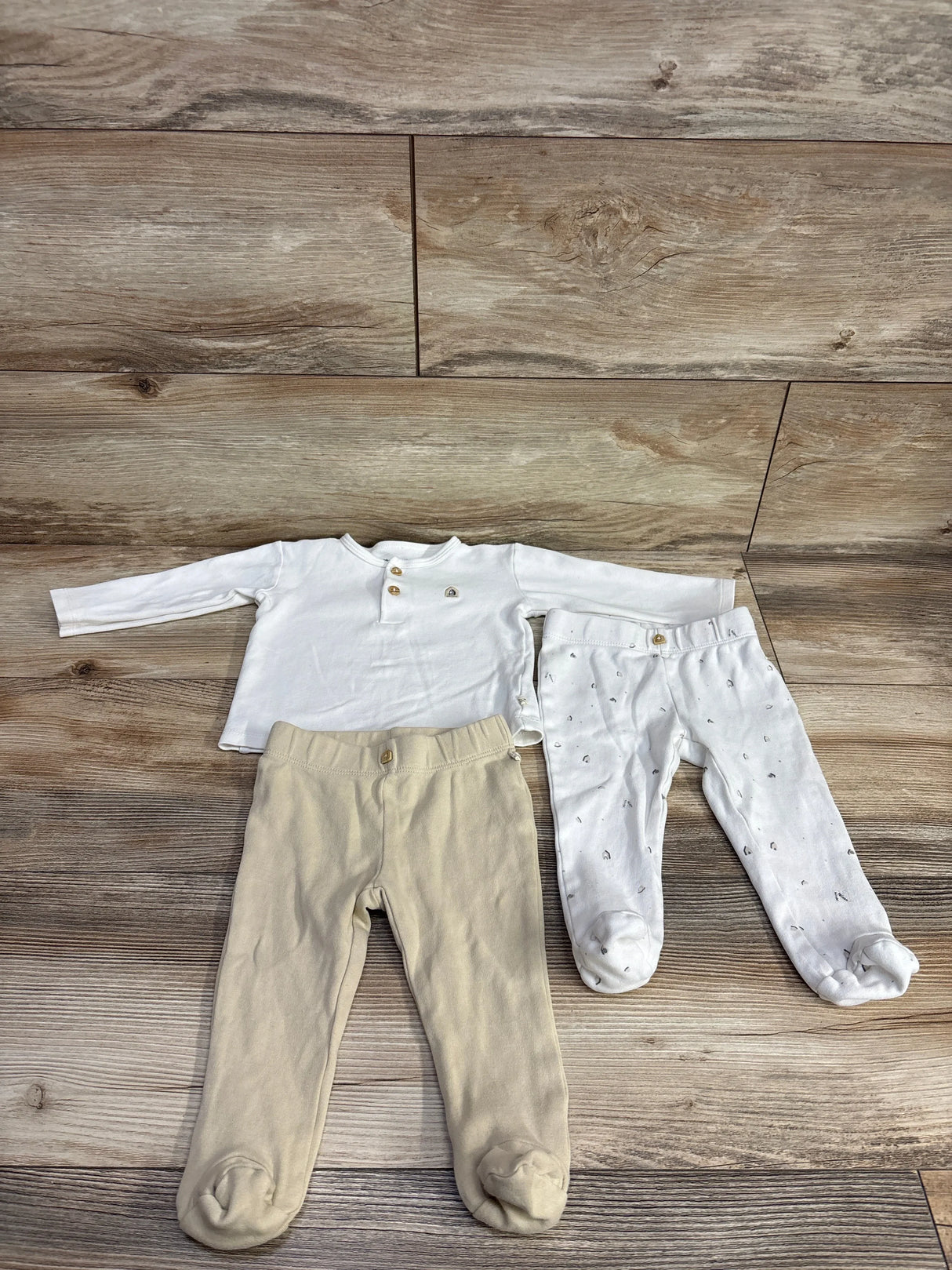 Infant long sleeve white shirt with beige and white footed pants on wood background