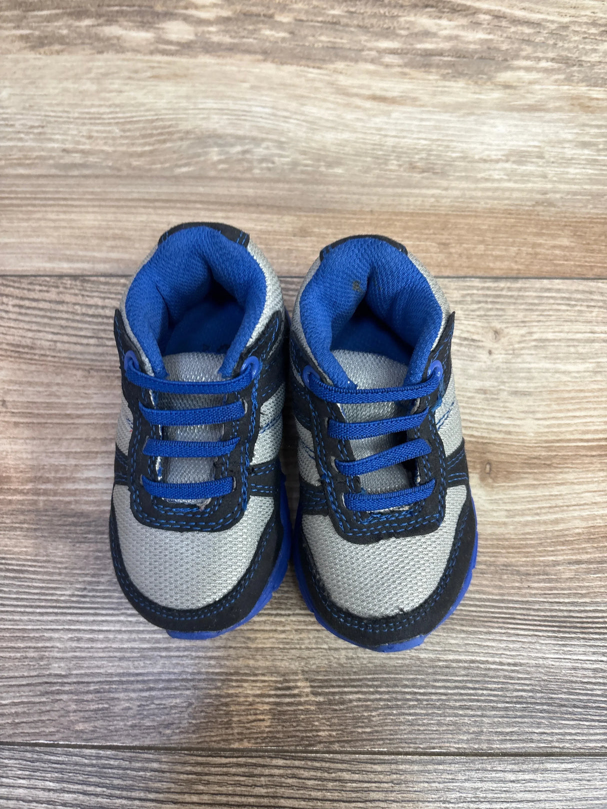 Top-down view of Children's Place casual toddler sneakers size 4C showcasing gray mesh upper, blue trim and elastic laces on wooden floor