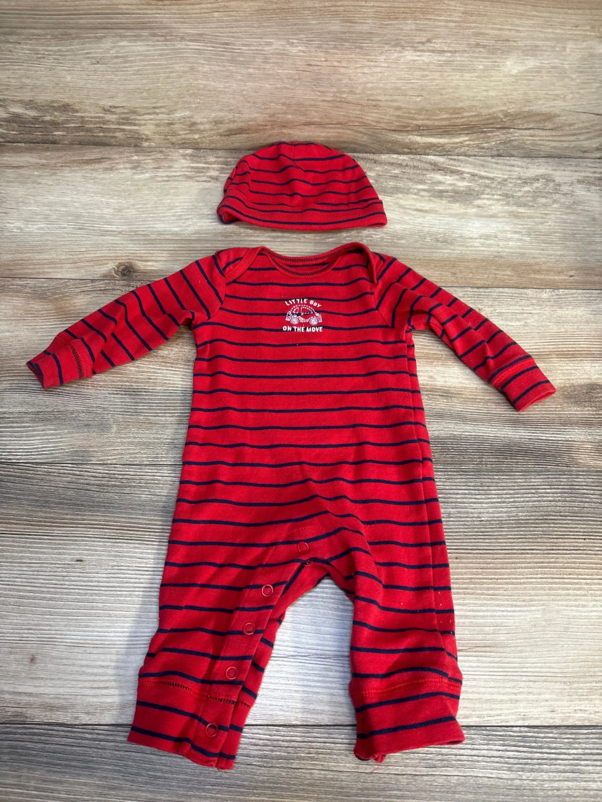 Red and navy striped baby romper with matching hat, long sleeves, snap closure, and text detail.