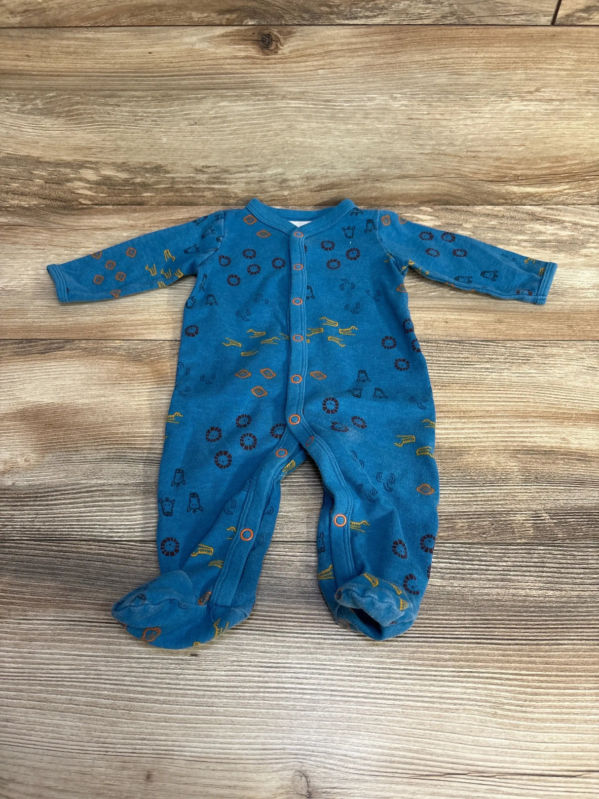 Front flat lay of Carter's blue footed sleeper size 3M showing all-over animal-print icons and front snap closure on wood background