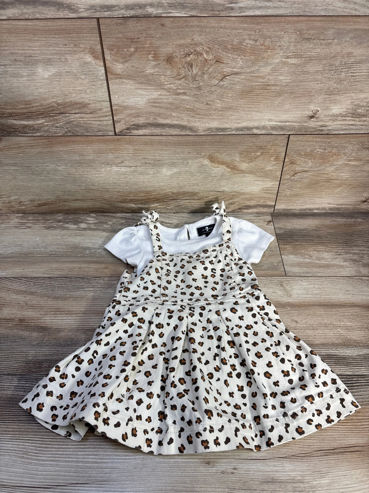Front view of 7 For All Mankind two-piece set showcasing a white ribbed shirt and leopard-print skirtall on wood flooring