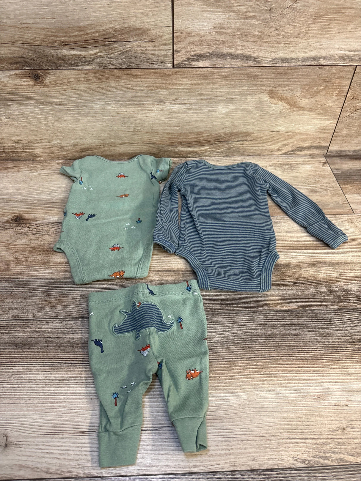 Baby boy bodysuits and pants set with dinosaur and animal prints on wood background