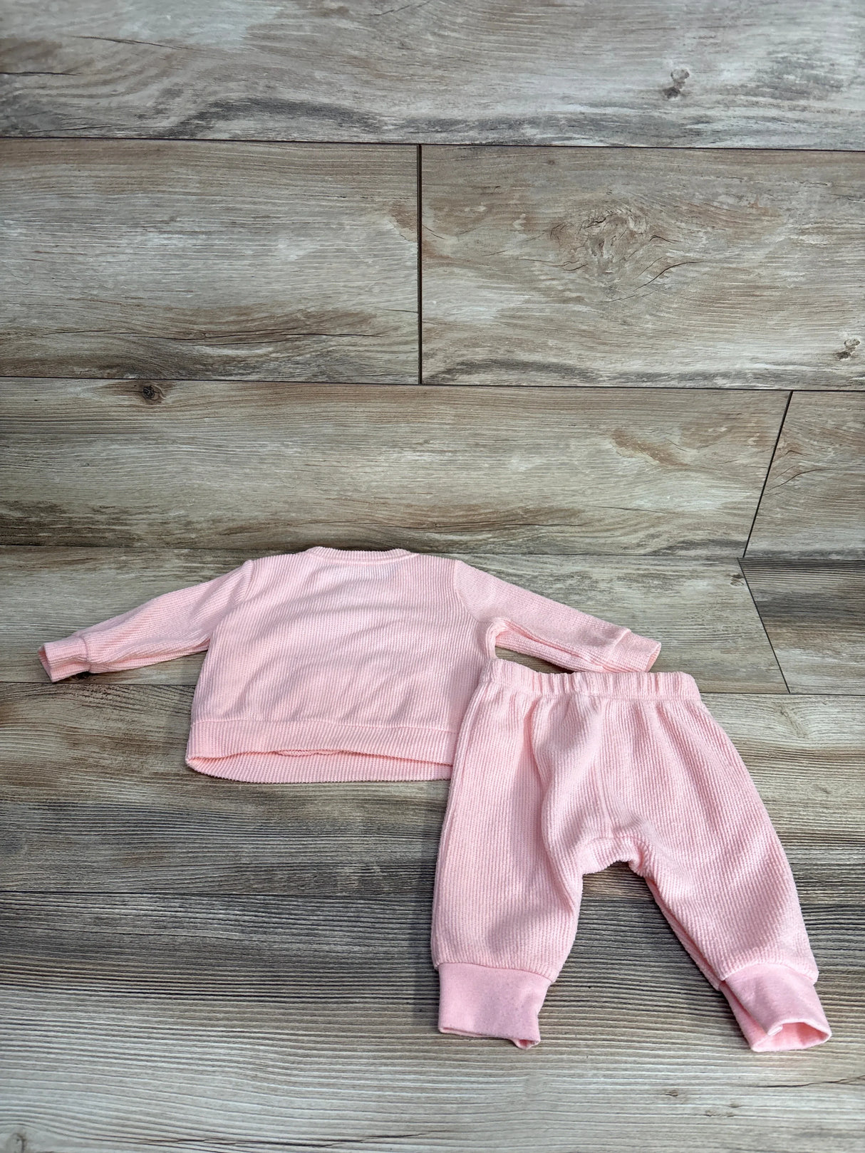 Pink ribbed baby outfit set with long sleeve top and pants on wood background