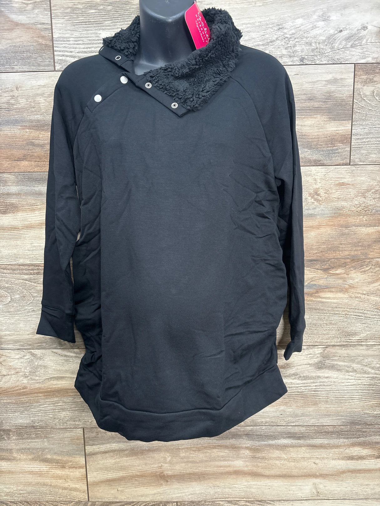 Black long-sleeve pullover with button and fleece collar on mannequin against wooden background