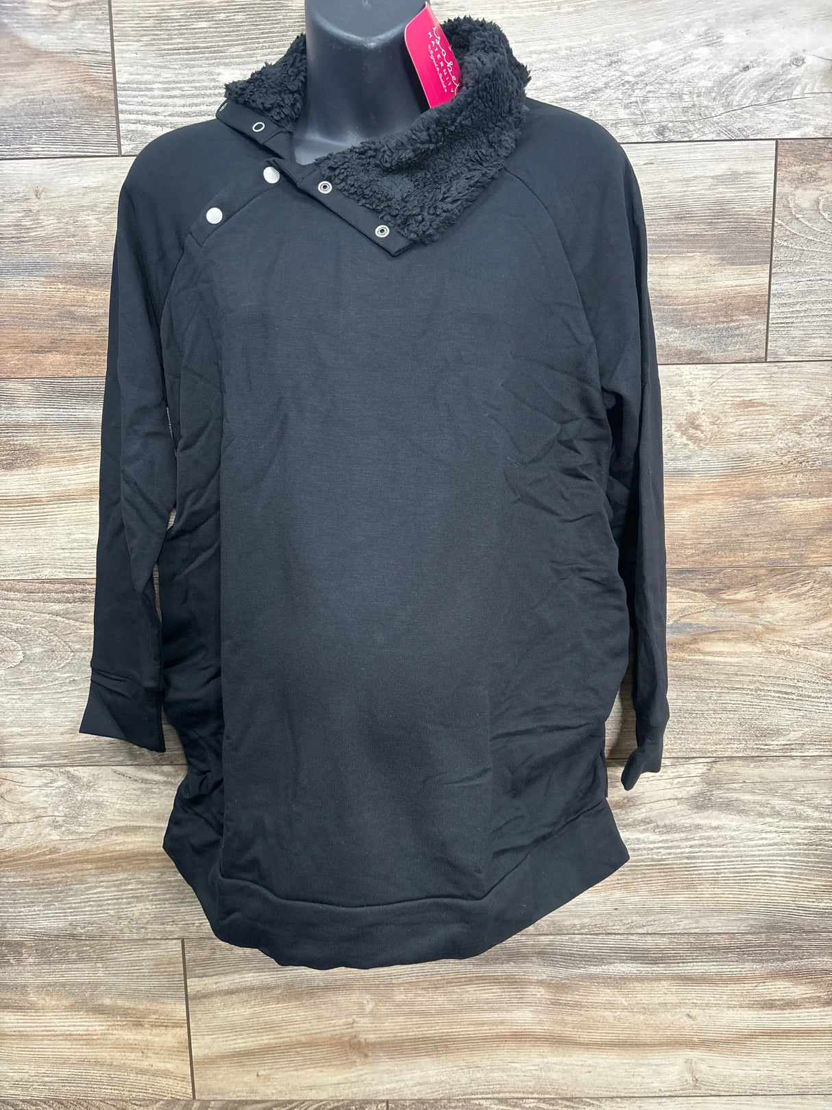 Black long-sleeve pullover with button and fleece collar on mannequin against wooden background