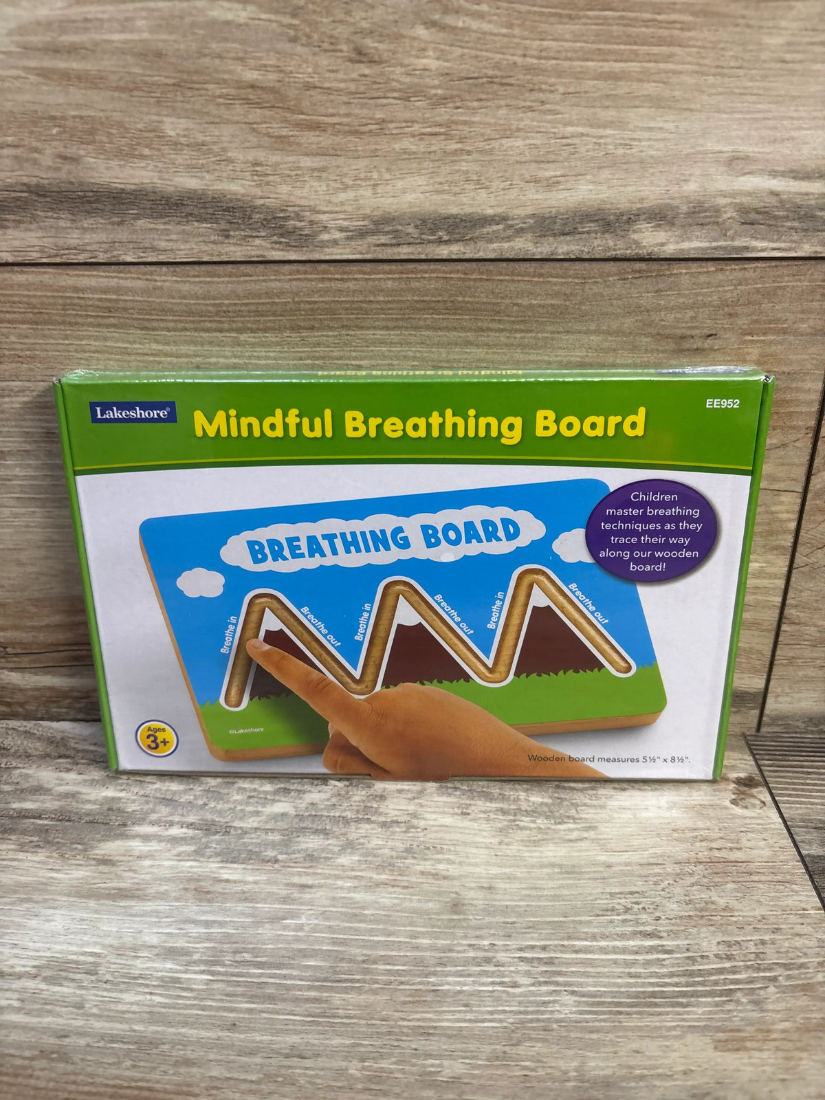 Front view of Lakeshore Mindful Breathing Board packaging showing a finger tracing the wooden breathing path on a wood surface