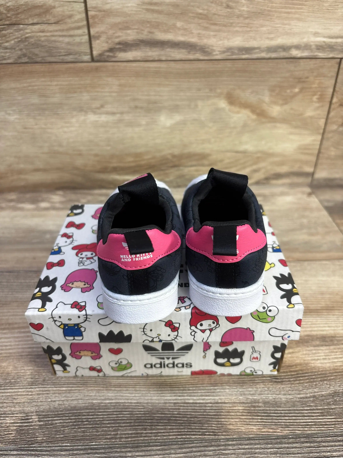 Rear view of Adidas Hello Kitty sneakers showing pink heel tab with HELLO KITTY AND FRIENDS on Hello Kitty shoebox
