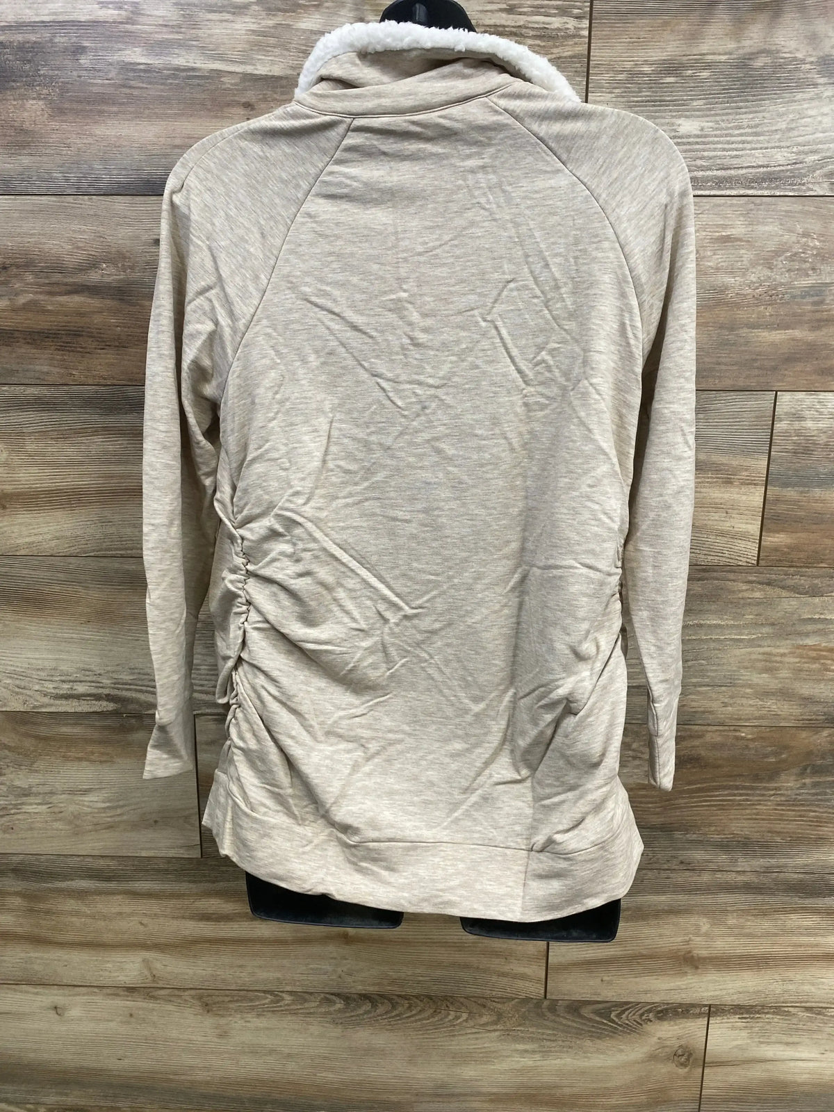 Back view of Isabel maternity oatmeal sweatshirt with sherpa-lined snap collar and side ruching on wood background
