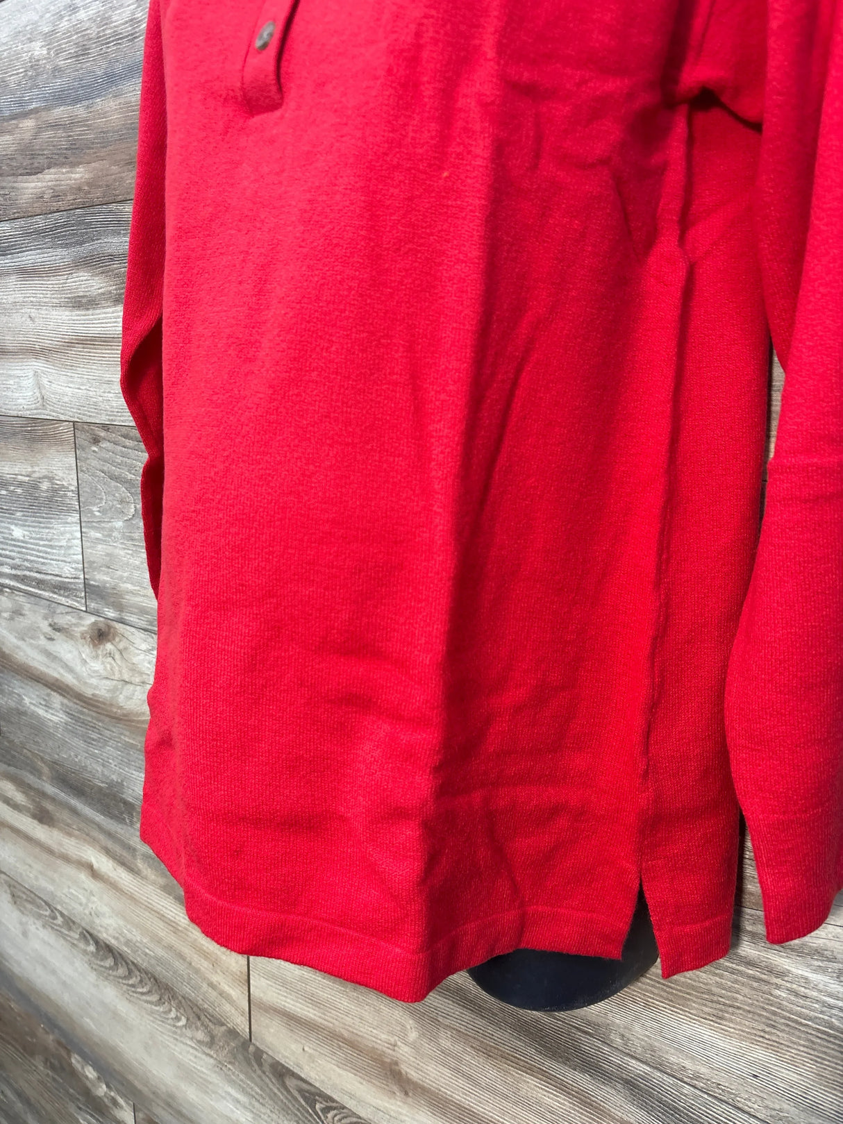 Close-up of Gap Maternity CashSoft polo sweater in red, size M, showing side hem slit and long sleeve on wooden background