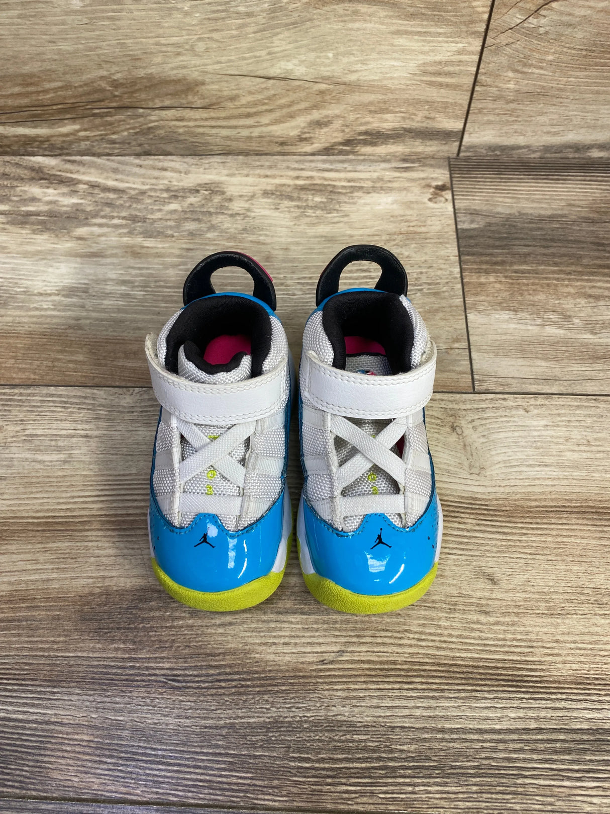 Top view of Air Jordan 6 Rings TD sneakers in white with blue fury and yellow accents on wood plank floor