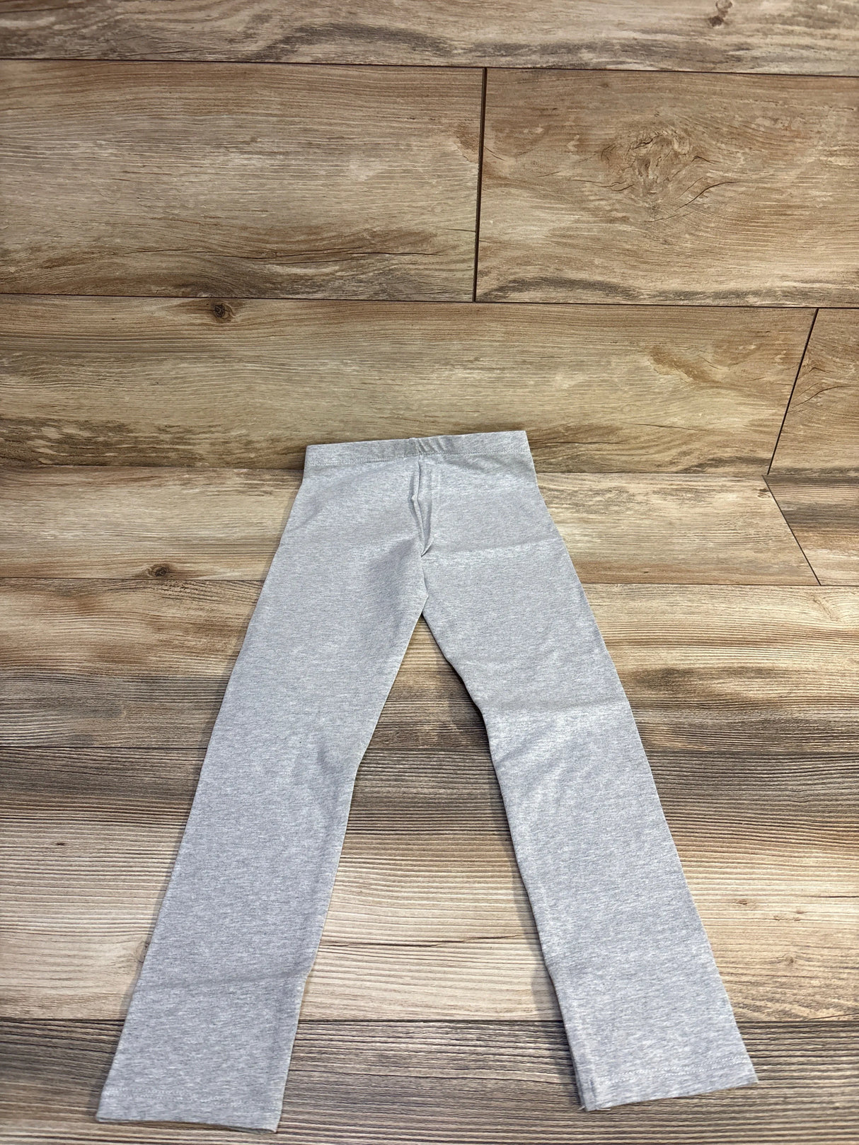 Flat-lay of Cat & Jack toddler leggings, size 5T, showing elastic waistband and straight legs on wooden floor background