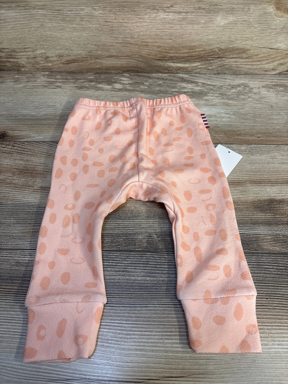 Peach baby pants with polka dot pattern displayed on wood background