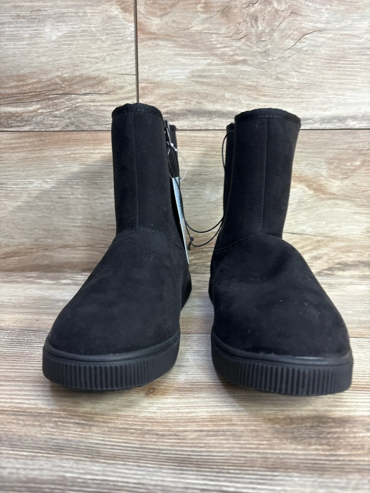Pair of black suede children's boots with side zippers on wooden floor