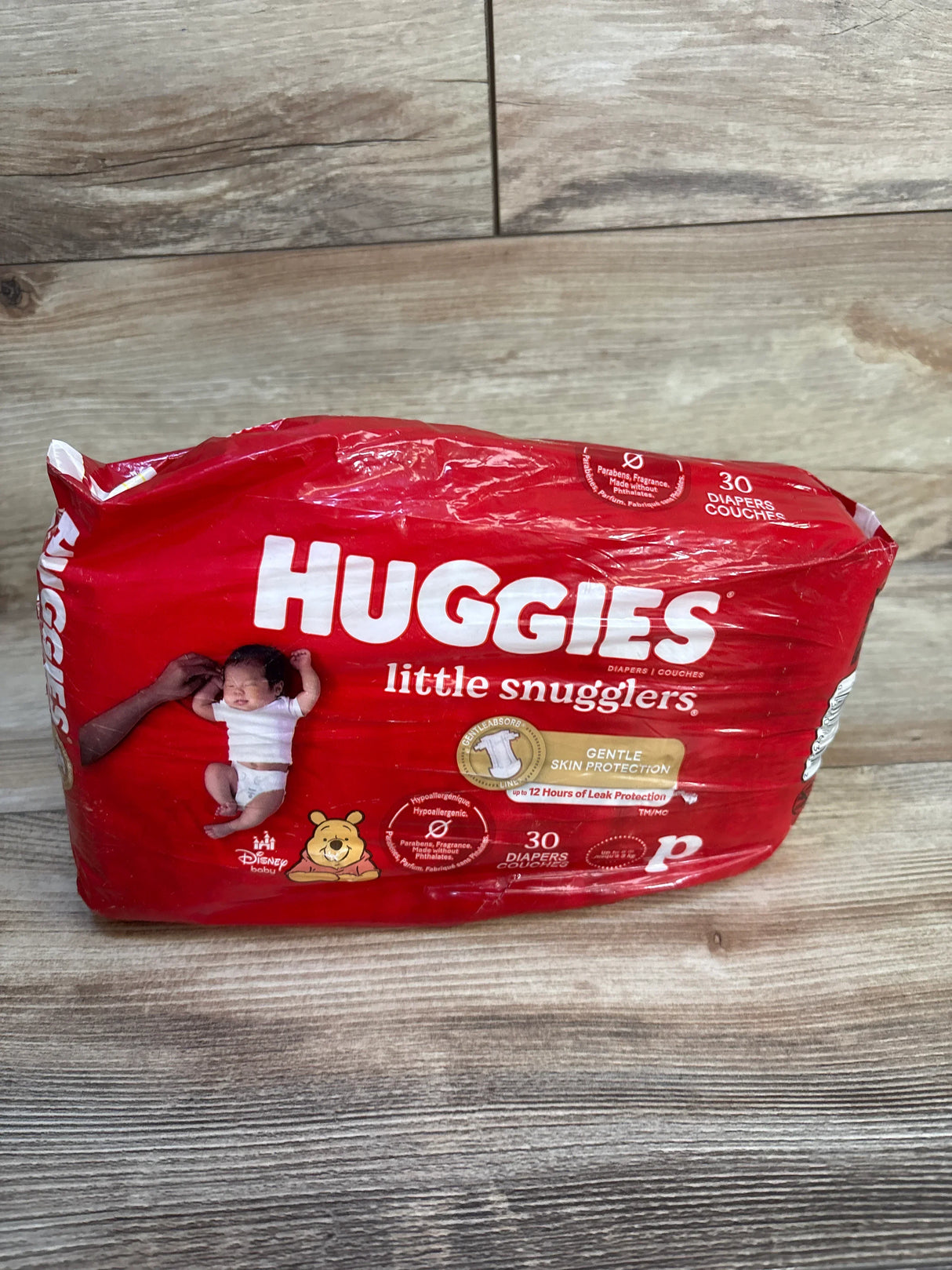 Front view of Huggies Little Snugglers preemie 30-count pack showing Gentle Skin Protection label and Winnie the Pooh graphic on wood floor