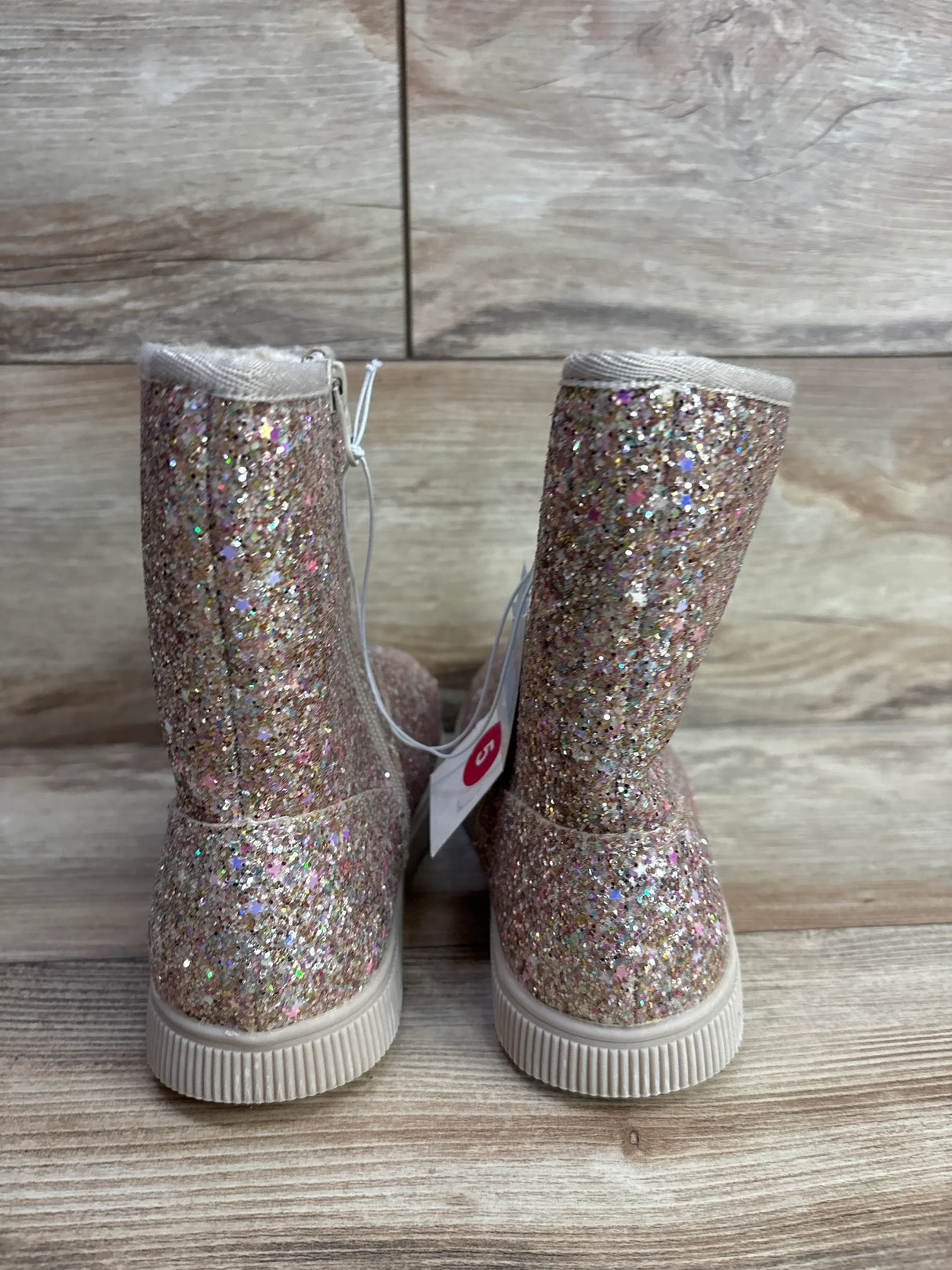 Pink glitter kids boots with sparkly finish on wooden floor