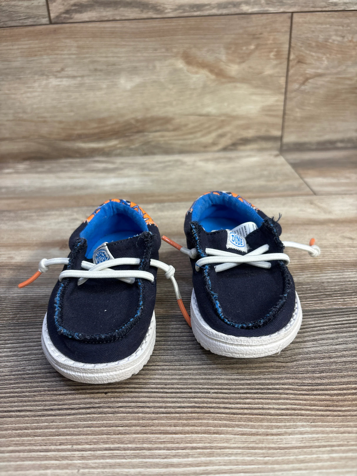 Front view of Hey Dude Wally navy toddler shoes showing shark-print lining and elastic laces on wood background