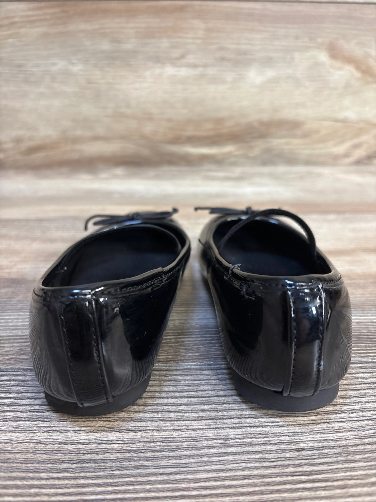 Rear view of black patent leather toddler dress shoes on wood floor