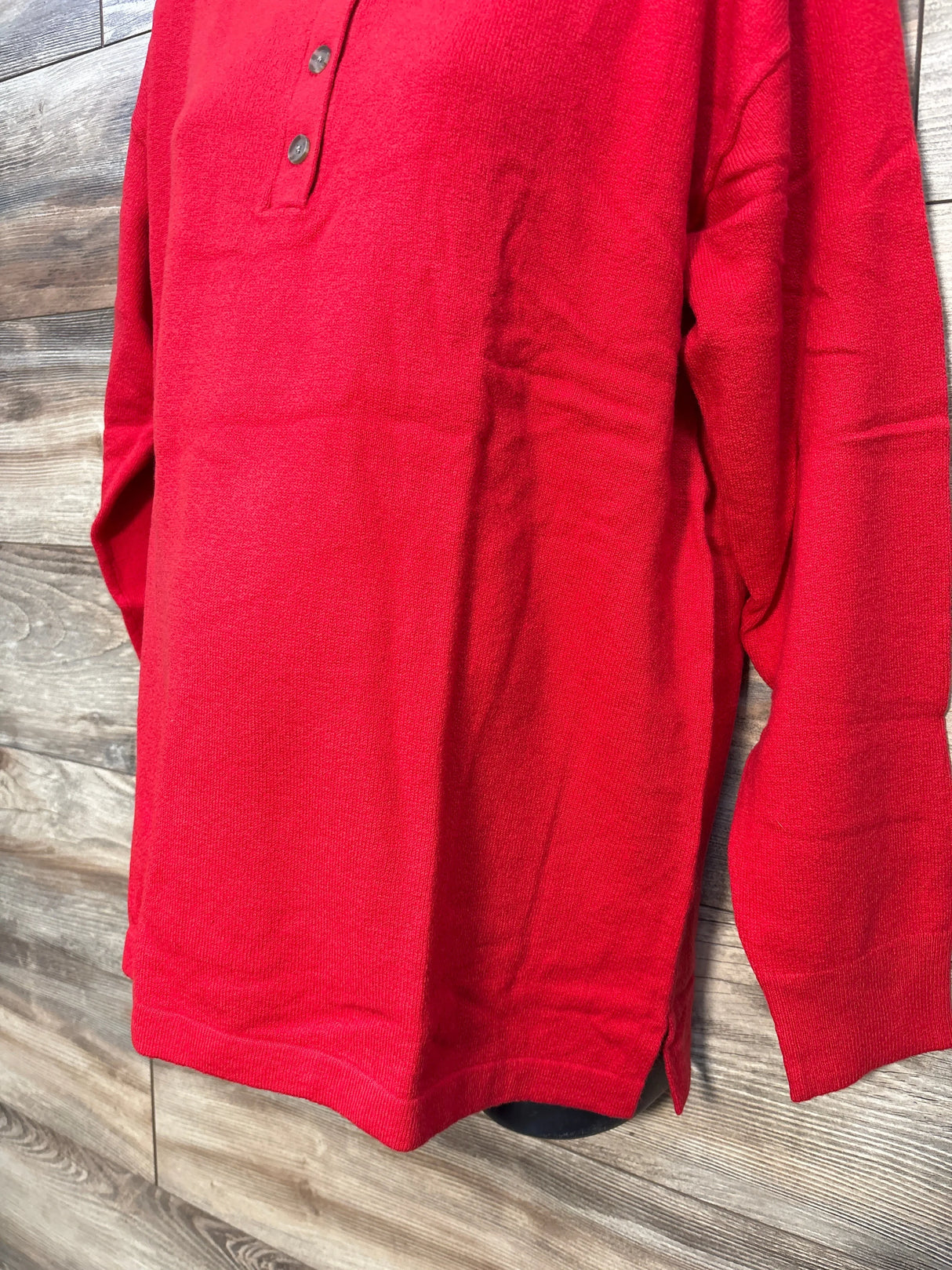 Red long sleeve knit henley shirt with buttons on rustic wood background