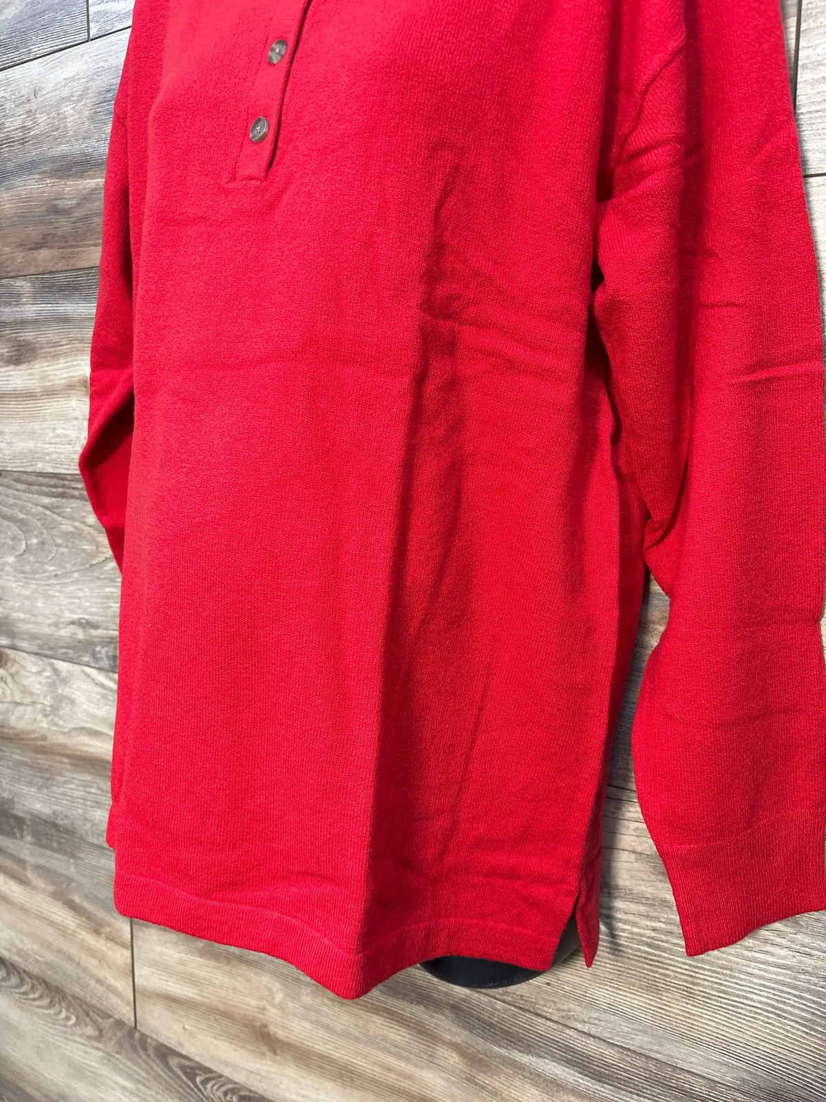 Red long sleeve knit henley shirt with buttons on rustic wood background