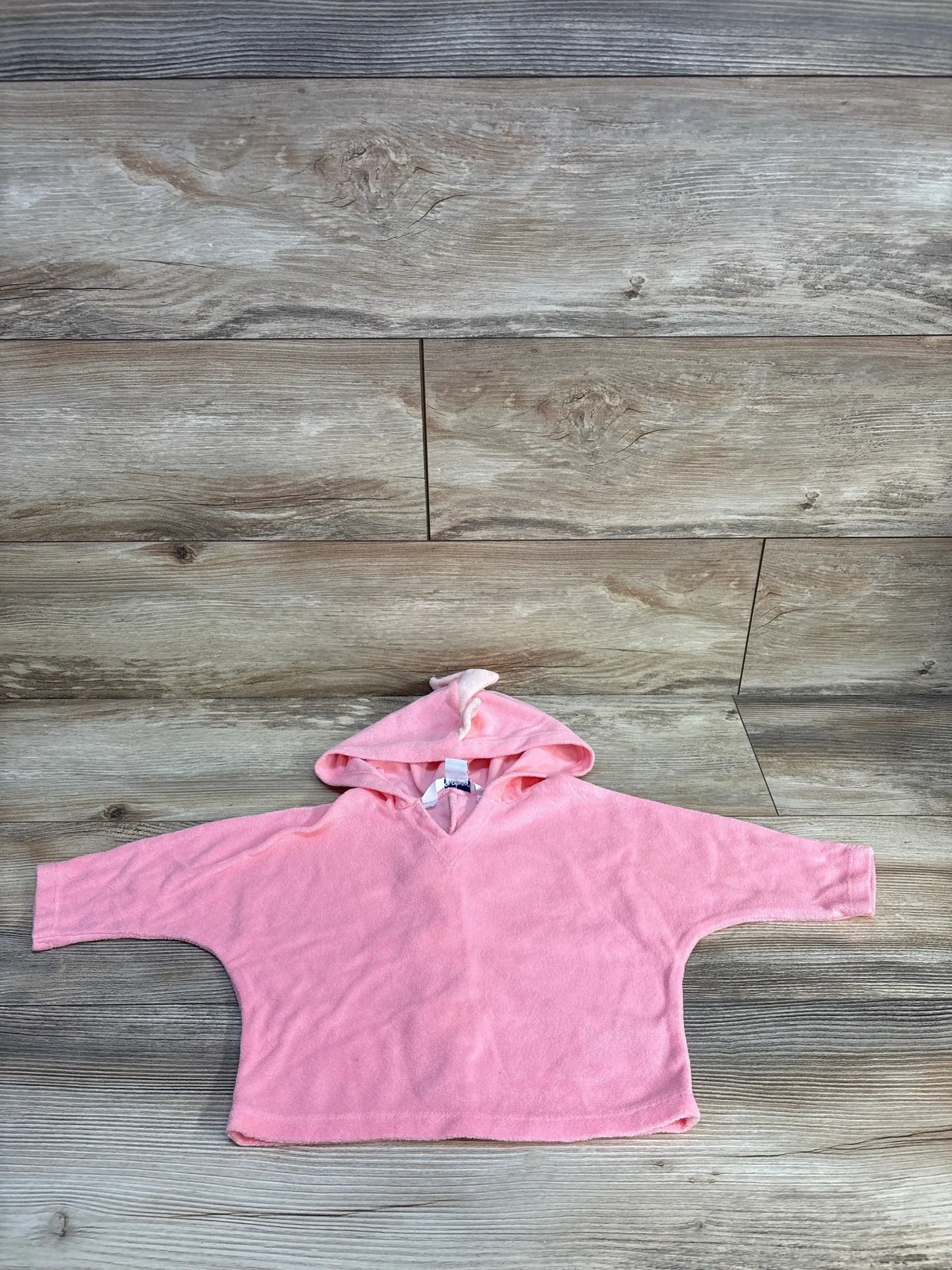 Flat lay of pink Old Navy toddler swim cover-up hoodie showcasing dinosaur hood ears and long sleeves on wooden floor