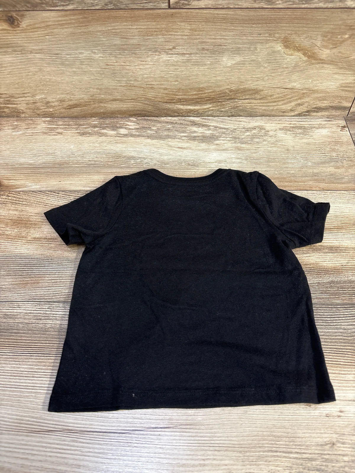 Back view of Way To Celebrate Halloween Frankenstein shirt showcasing its plain black back with a wood grain background