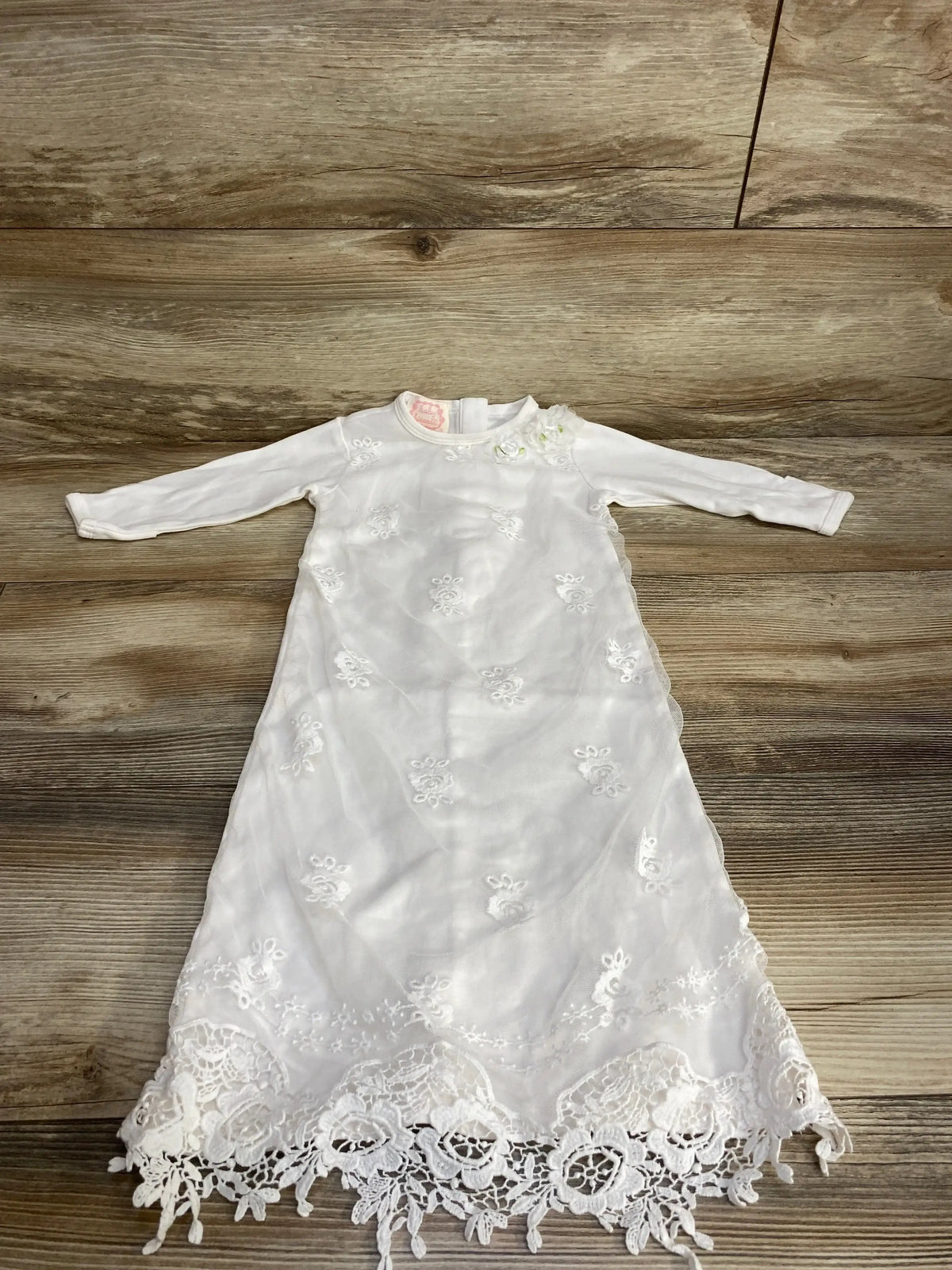 Flat lay of Baby Biscotti white lace christening gown, 3-6m, showing embroidered bodice and scalloped lace hem on wood