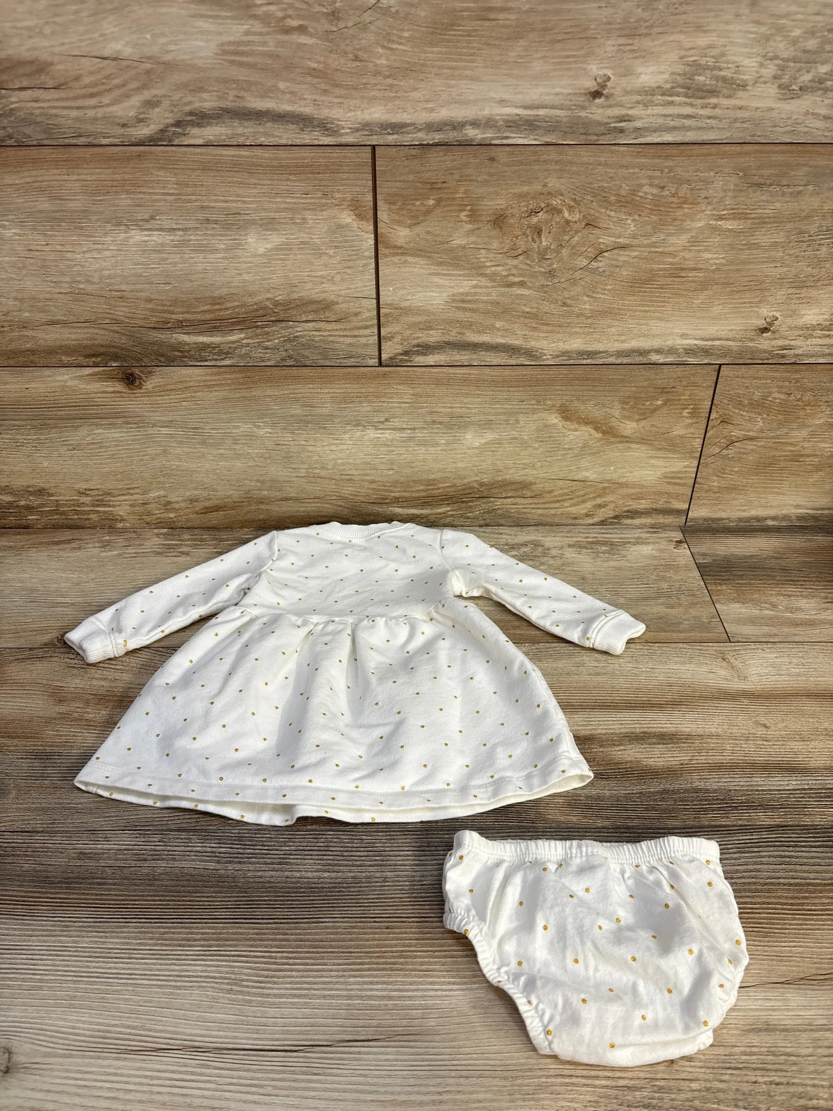 Top view of Carter’s polka dot sweatshirt dress and bloomers set showcasing white fabric and long sleeves on wood flooring