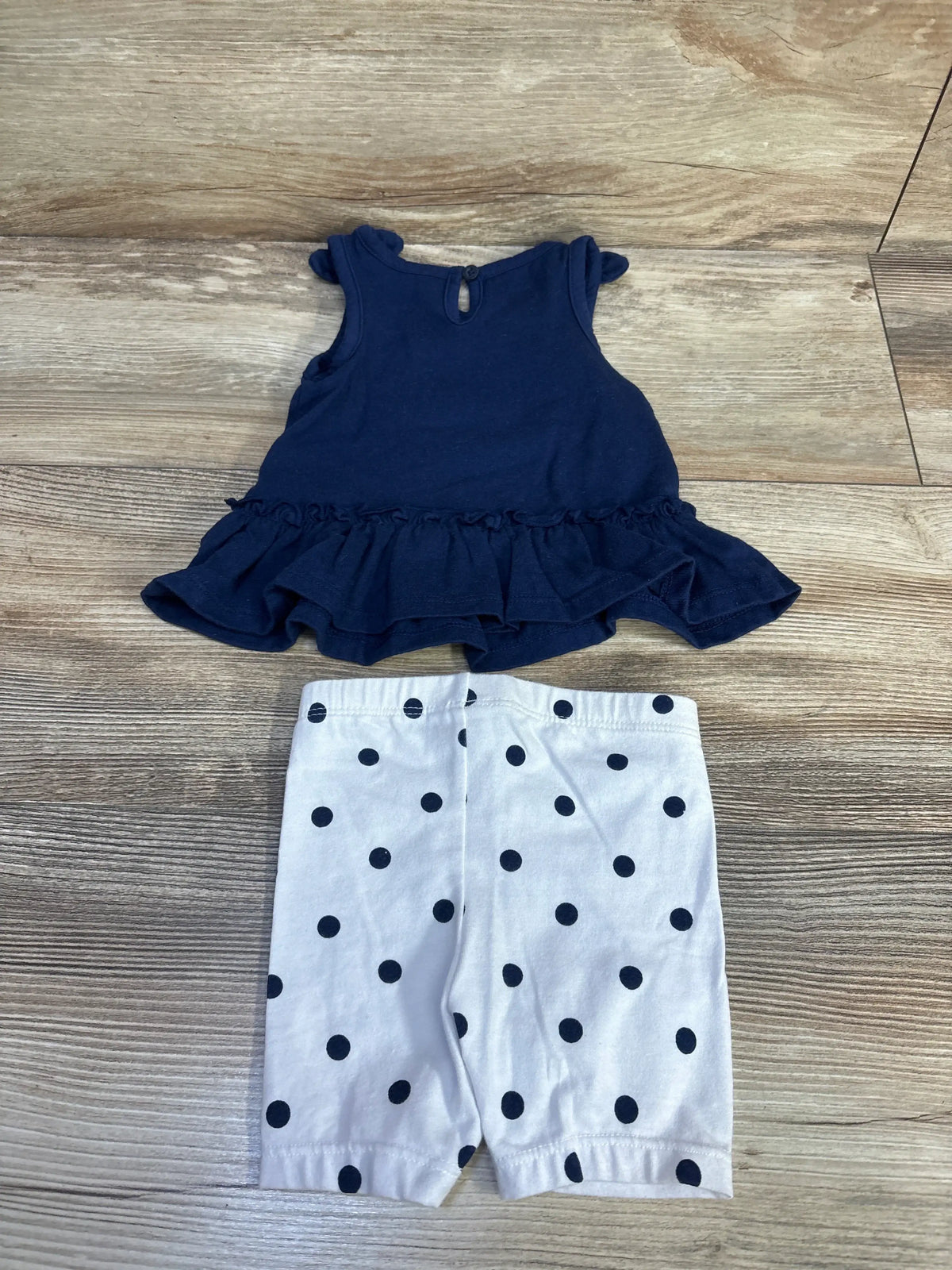 Front view of Nautica peplum top and leggings set showcasing navy ruffles and polka-dot leggings on a wood floor
