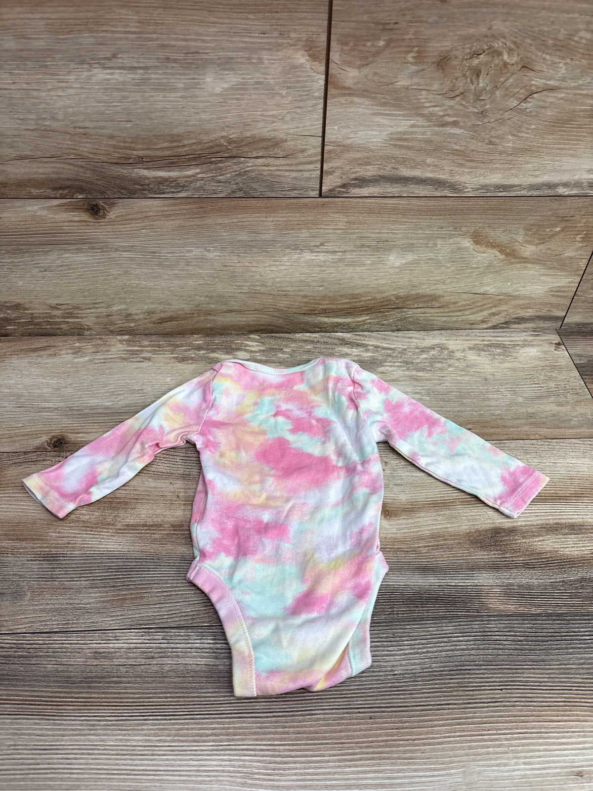 Old Navy tie-dye pink and blue long sleeve baby bodysuit for 6-12 months on wood background