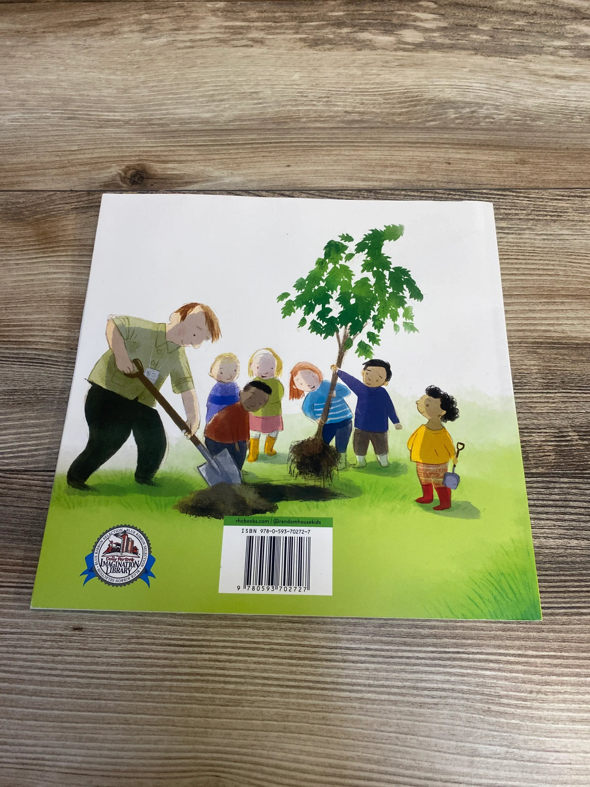 Back of This Is the Tree We Planted paperback showing children planting a tree illustration and barcode on a wood tabletop