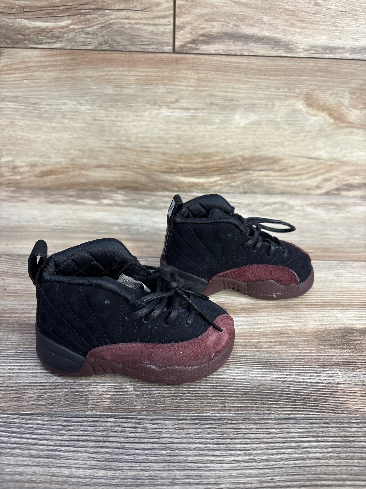 Black and burgundy toddler sneakers on wooden floor background