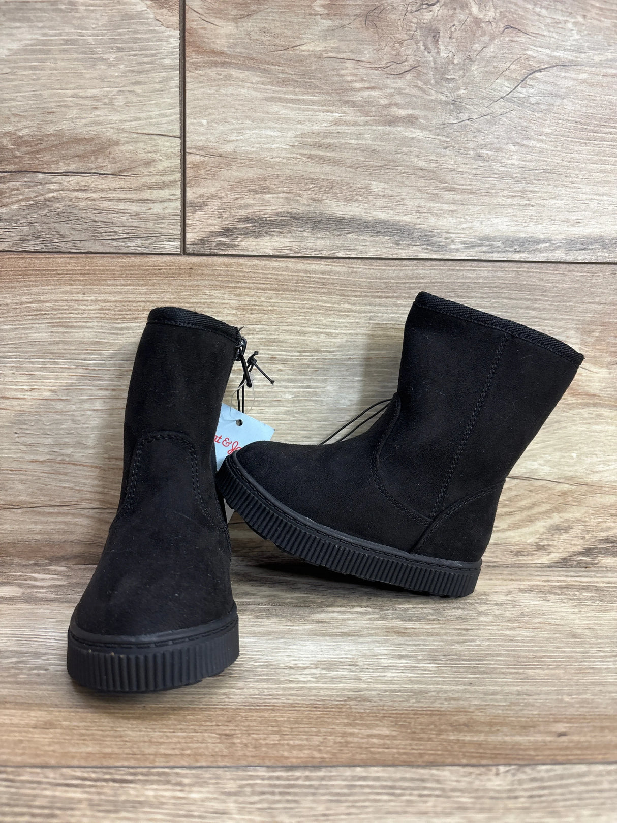 Black suede kids boots with rubber soles displayed on wooden floor