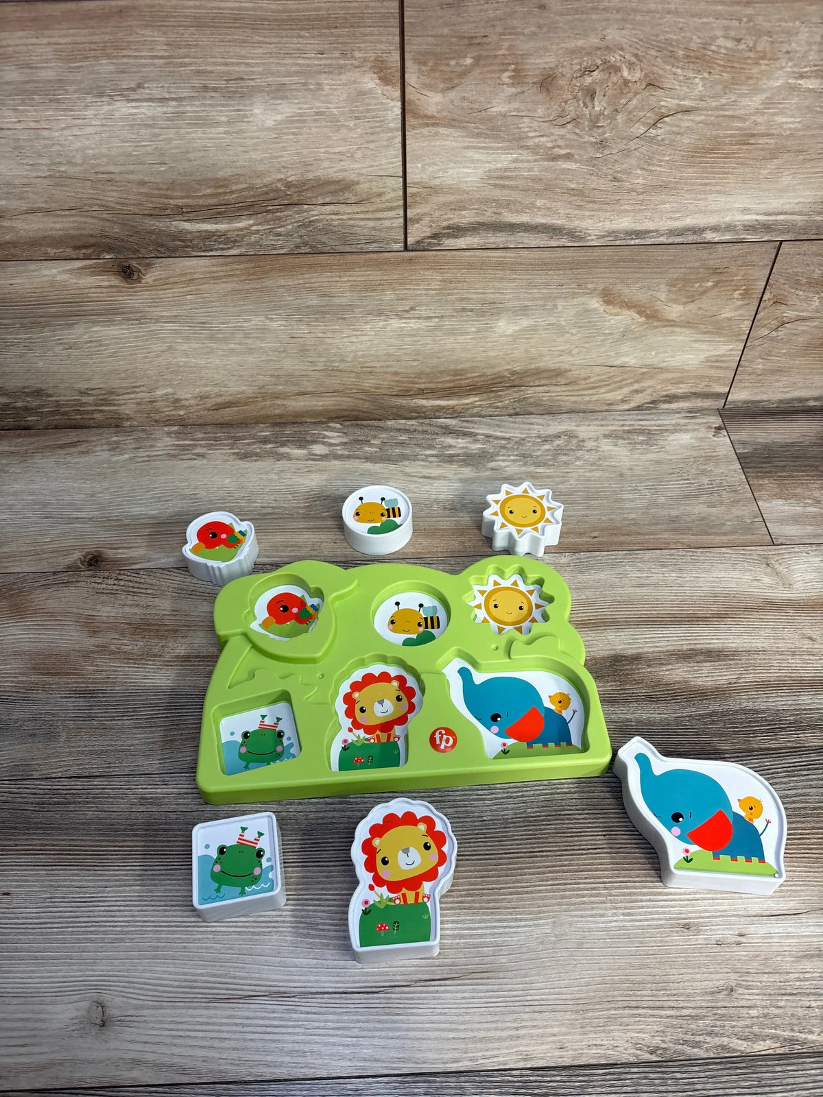 Fisher-Price animal shape puzzle with lion, elephant, frog, and sun on wood background