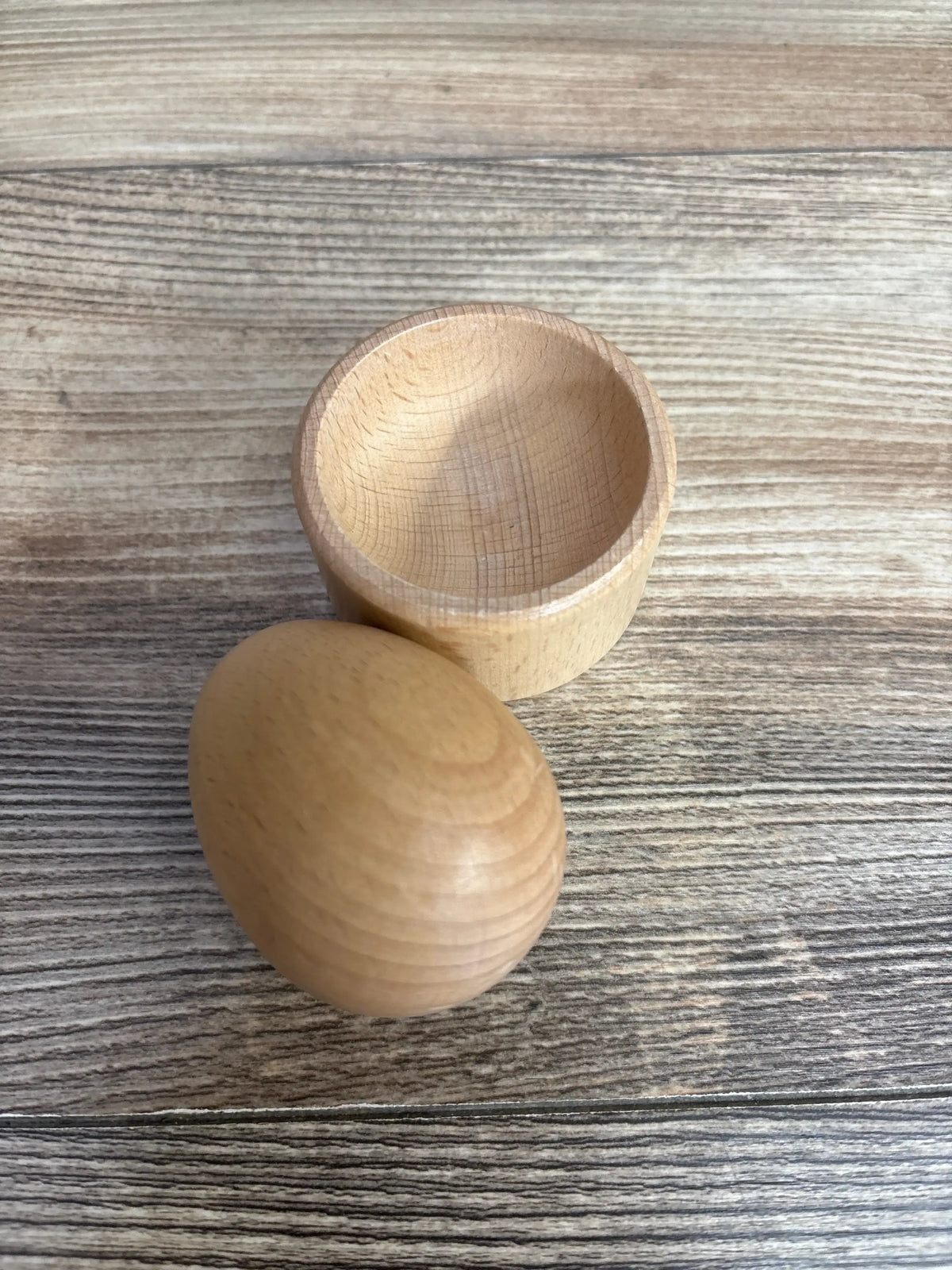 Wooden toy egg and cup set on a wood grain surface, educational baby toy