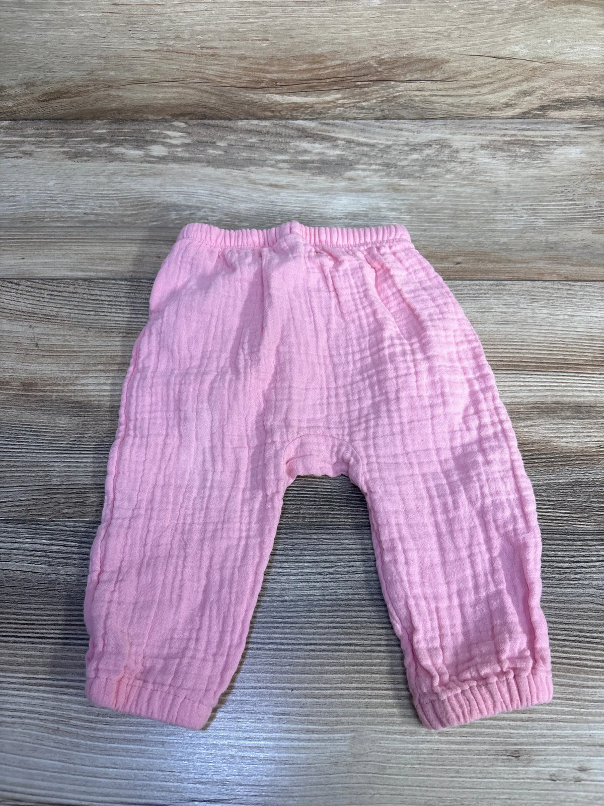 Front view of pink Old Navy gauze pull-on pants showcasing drawstring waist and ribbed cuffs on wood-grain background