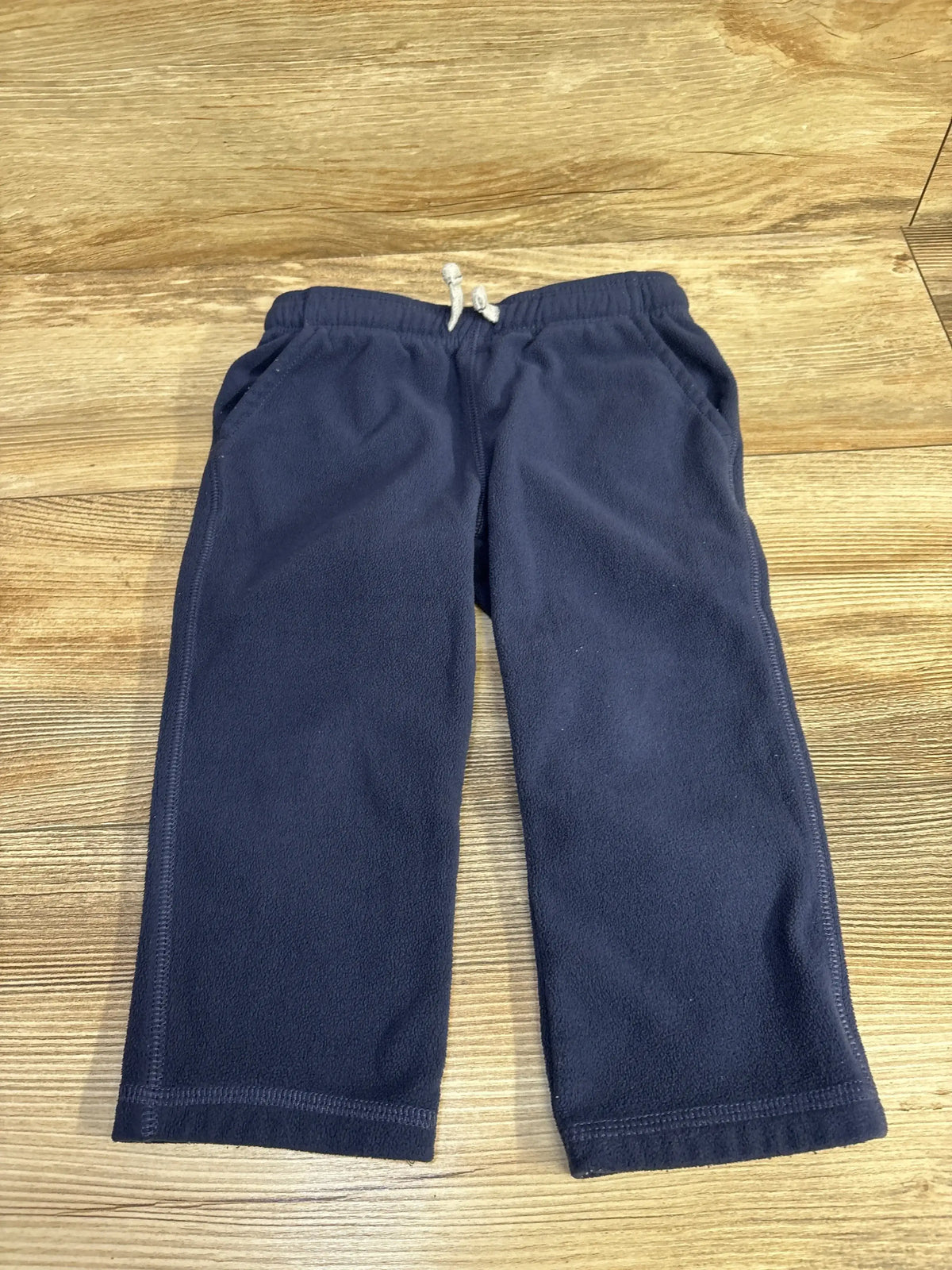 Navy blue fleece toddler pants with drawstring on wood background