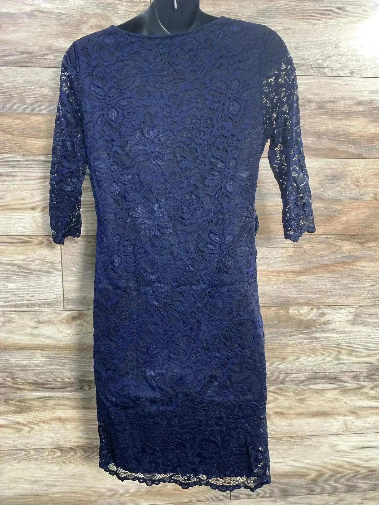 Front view of navy Pink Blush fitted lace dress with 3/4 sleeves on black mannequin against wood plank background