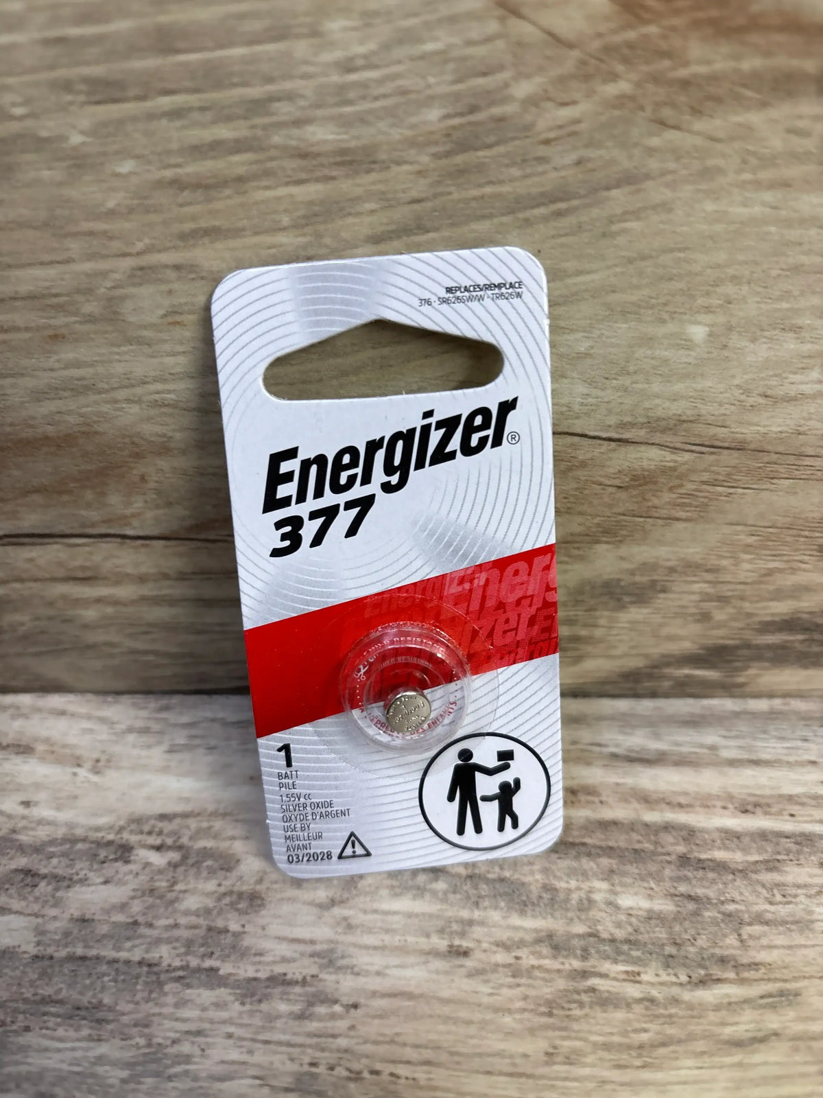 Angled front of Energizer 377 button cell pack showing single zero mercury battery in blister on wooden surface