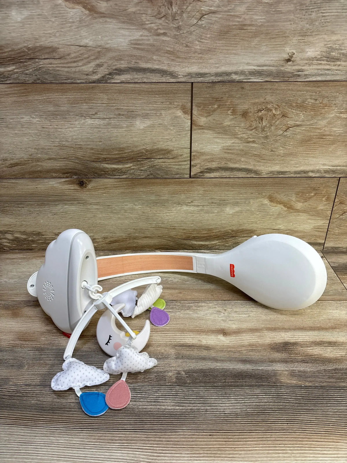 Overhead view of Fisher-Price Calming Clouds Crib Mobile & Soother showing plush clouds and colorful raindrops on wooden floor