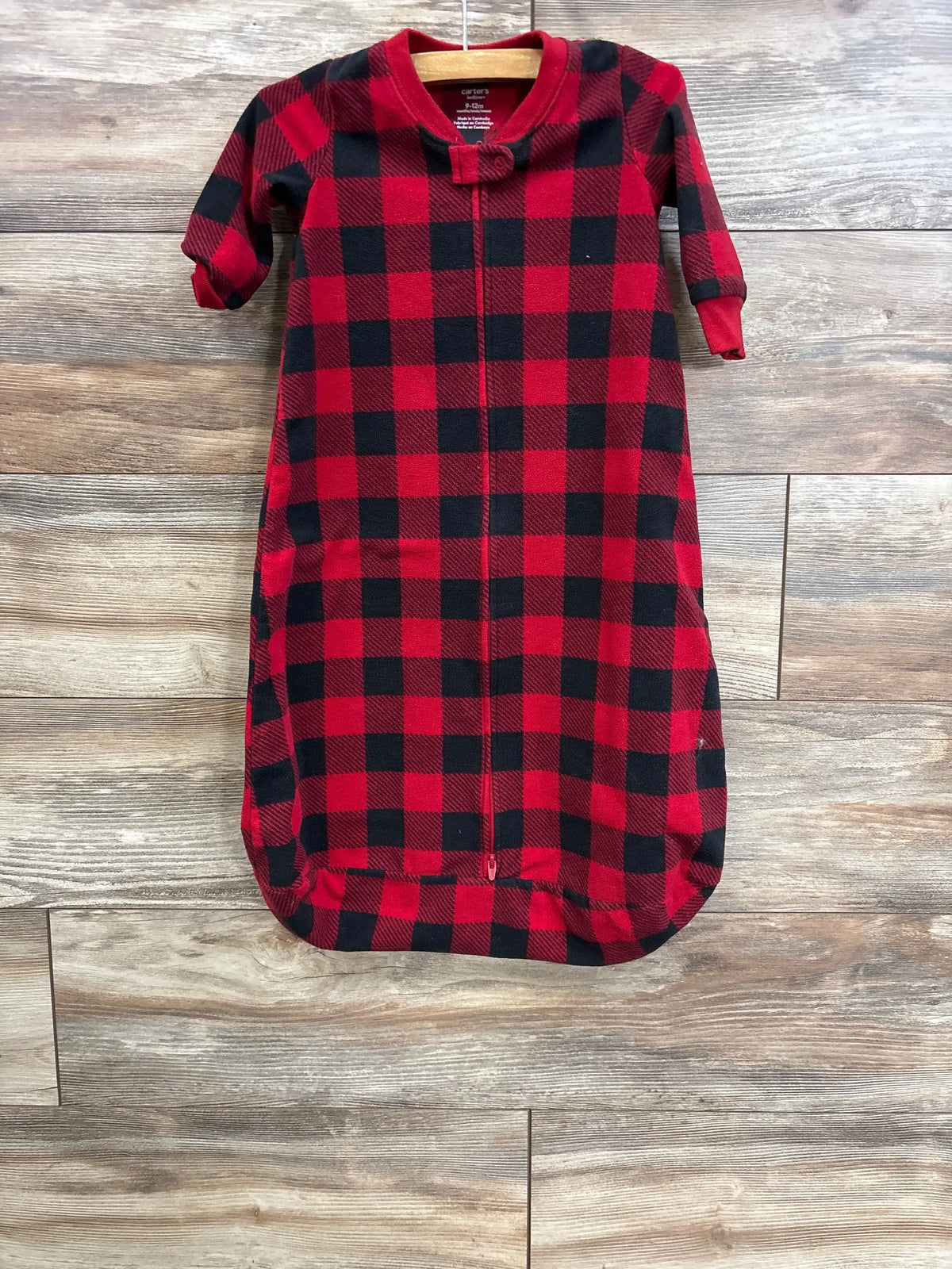 Front view of Carter’s red and black buffalo-plaid fleece sleep sack with center zipper and rounded bottom on wood background