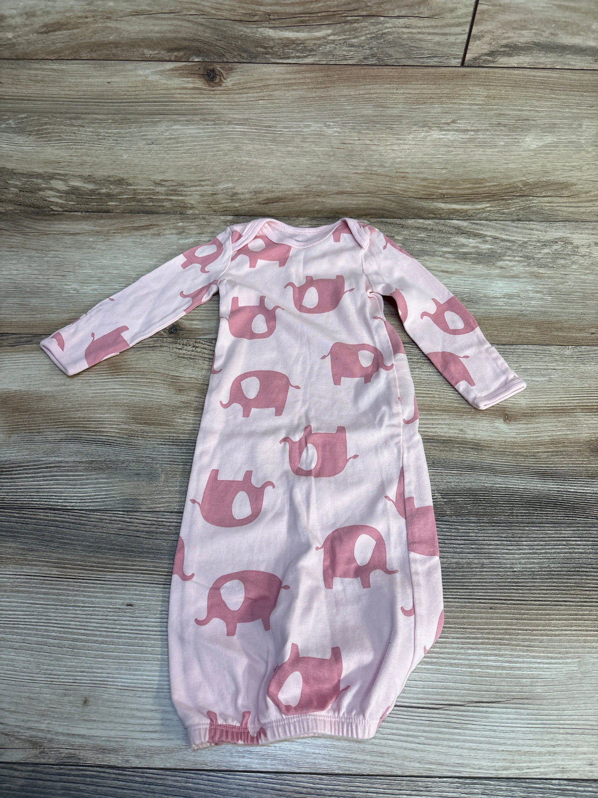 Flat lay of pink sleeper sack with darker pink elephant print, long sleeves and elastic gathered hem on light wood background