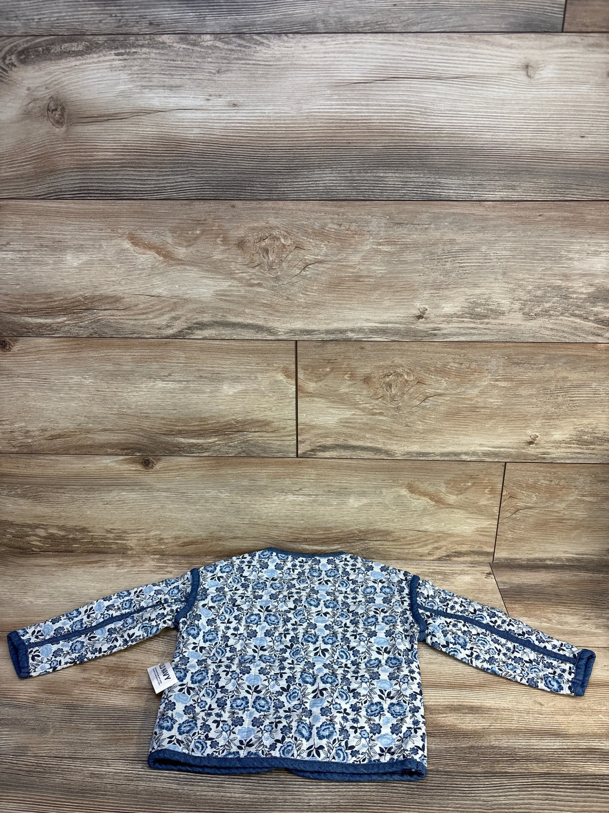 Blue floral long sleeve baby shirt with navy trim on wood background