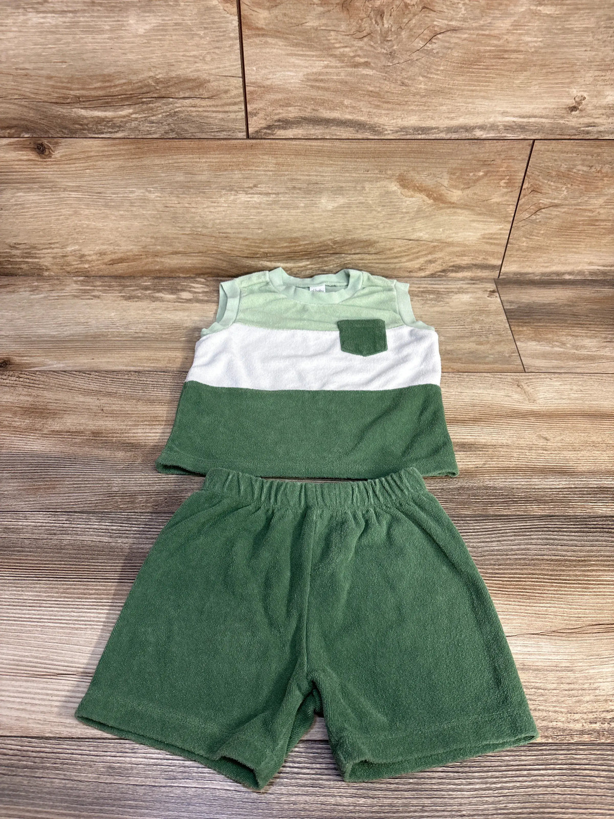 Front view of PL Baby terry tank top and shorts set showcasing green and white color blocking on a wood-look floor
