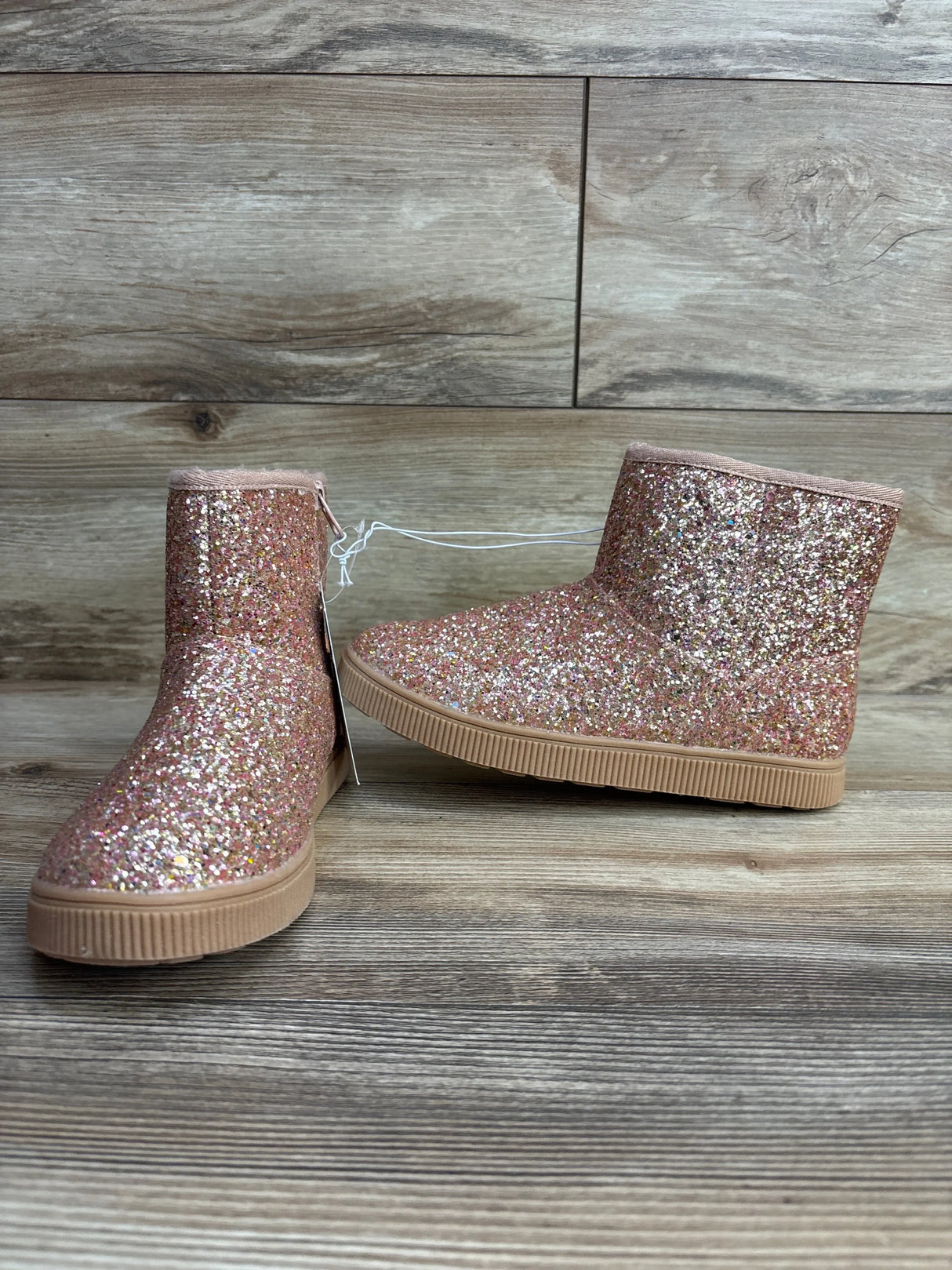 Sparkly pink glitter kids ankle boots with rubber soles on wood background