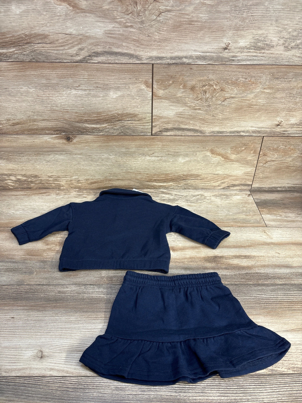 Navy blue baby sweater and skirt set on wooden floor background