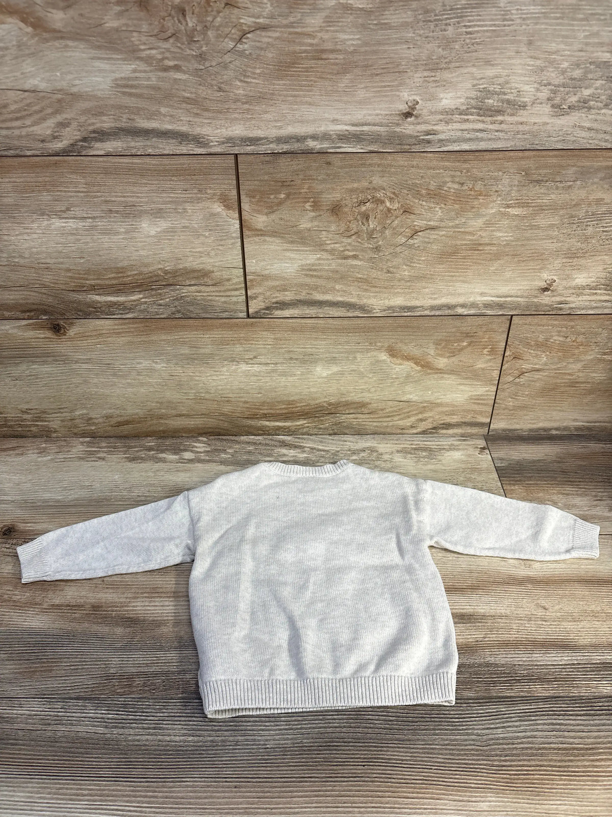 Front view of H&M fine-knit jumper sweater showcasing soft beige color and ribbed trim on a wood floor
