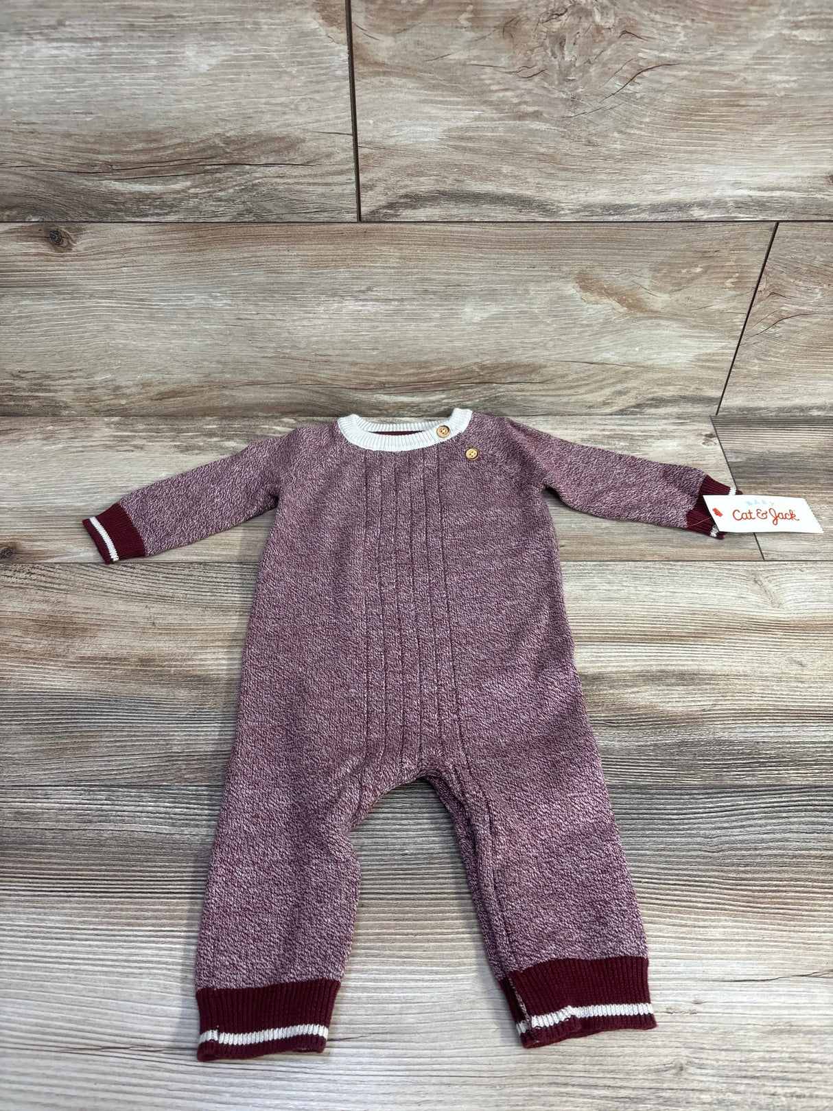 Maroon knit baby romper with white trim and buttons, Cat & Jack label, on wood floor