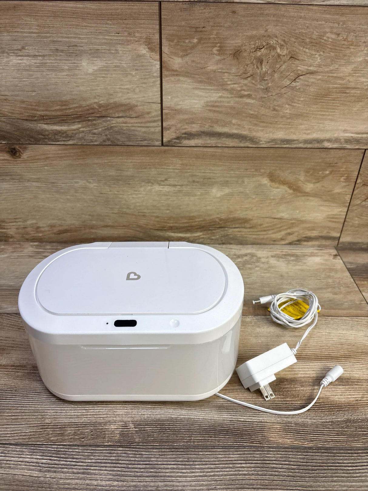 Front view of Munchkin Touch Free wipe warmer showing touch-free sensor and nightlight with adapter on wood background
